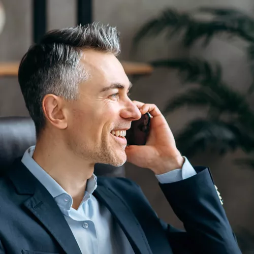 Freundlicher Immobilienmakler telefoniert mit einem Kunden im Büro Freundlicher Immobilienmakler telefoniert mit einem Kunden im Büro