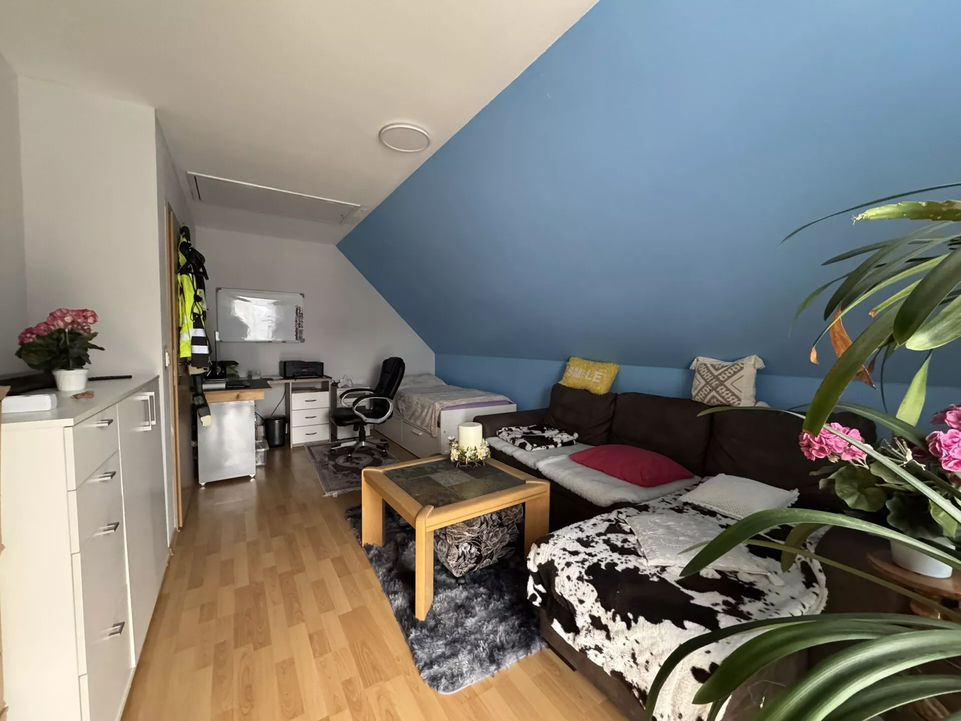 Zimmer im Dachgeschoss mit Dachschräge, Sitzbereich und Arbeitsplatz im Einfamilienhaus in Berlin-Falkenberg.